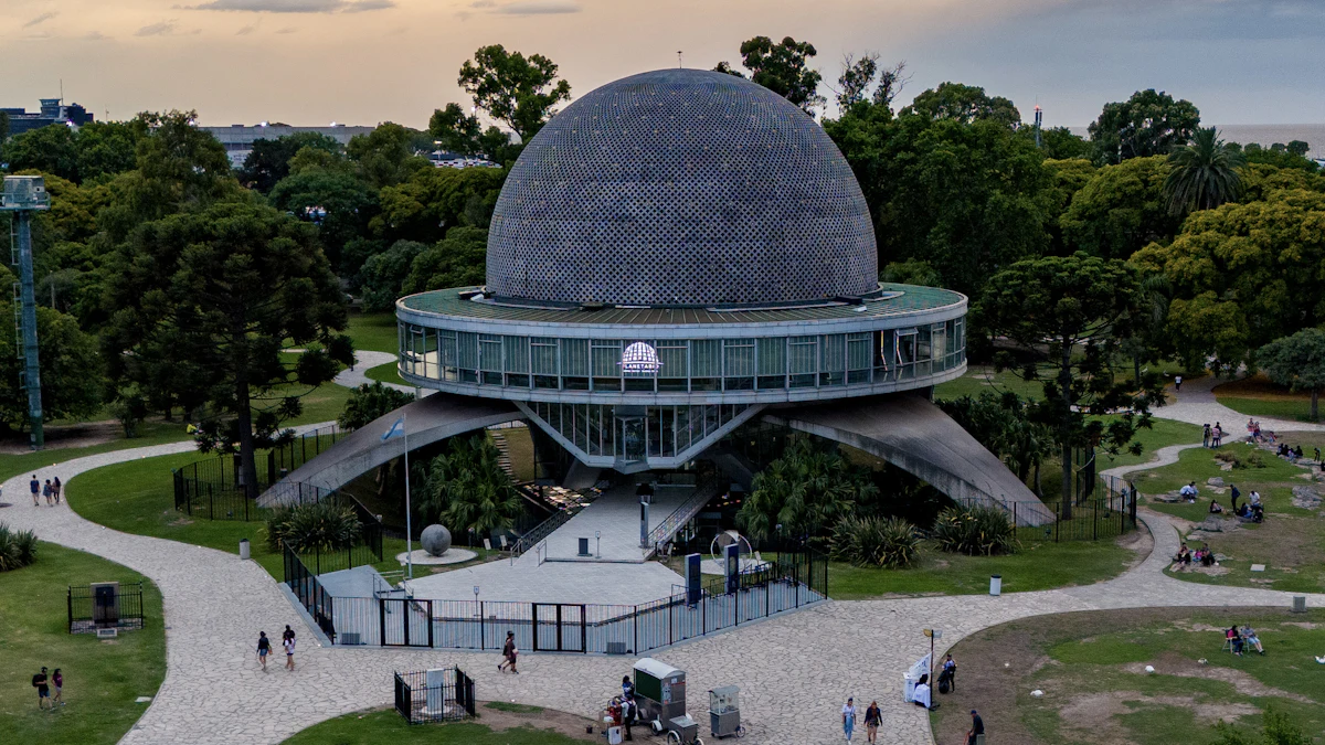 Aerial view of the domed Galileo Galilei Planetarium surrounded by park paths and trees at dusk