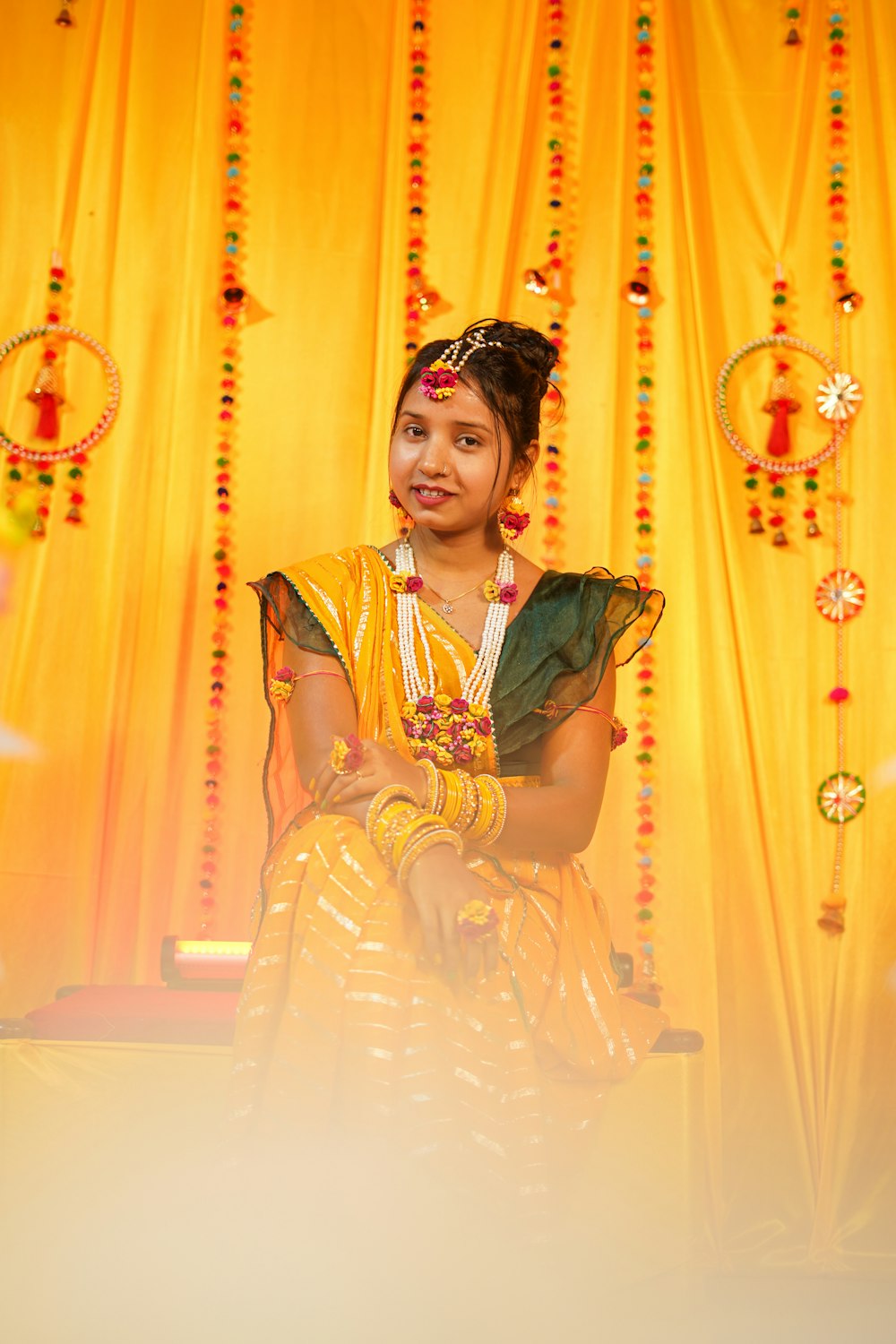 a young girl sitting in front of a yellow curtain