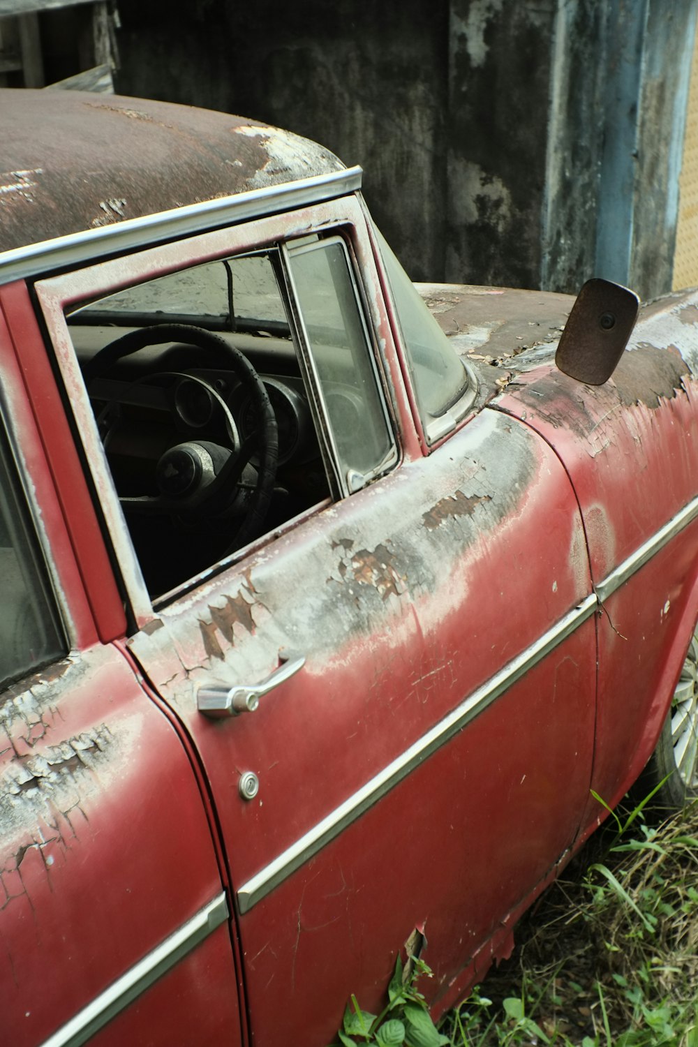 an old red car sitting in the grass