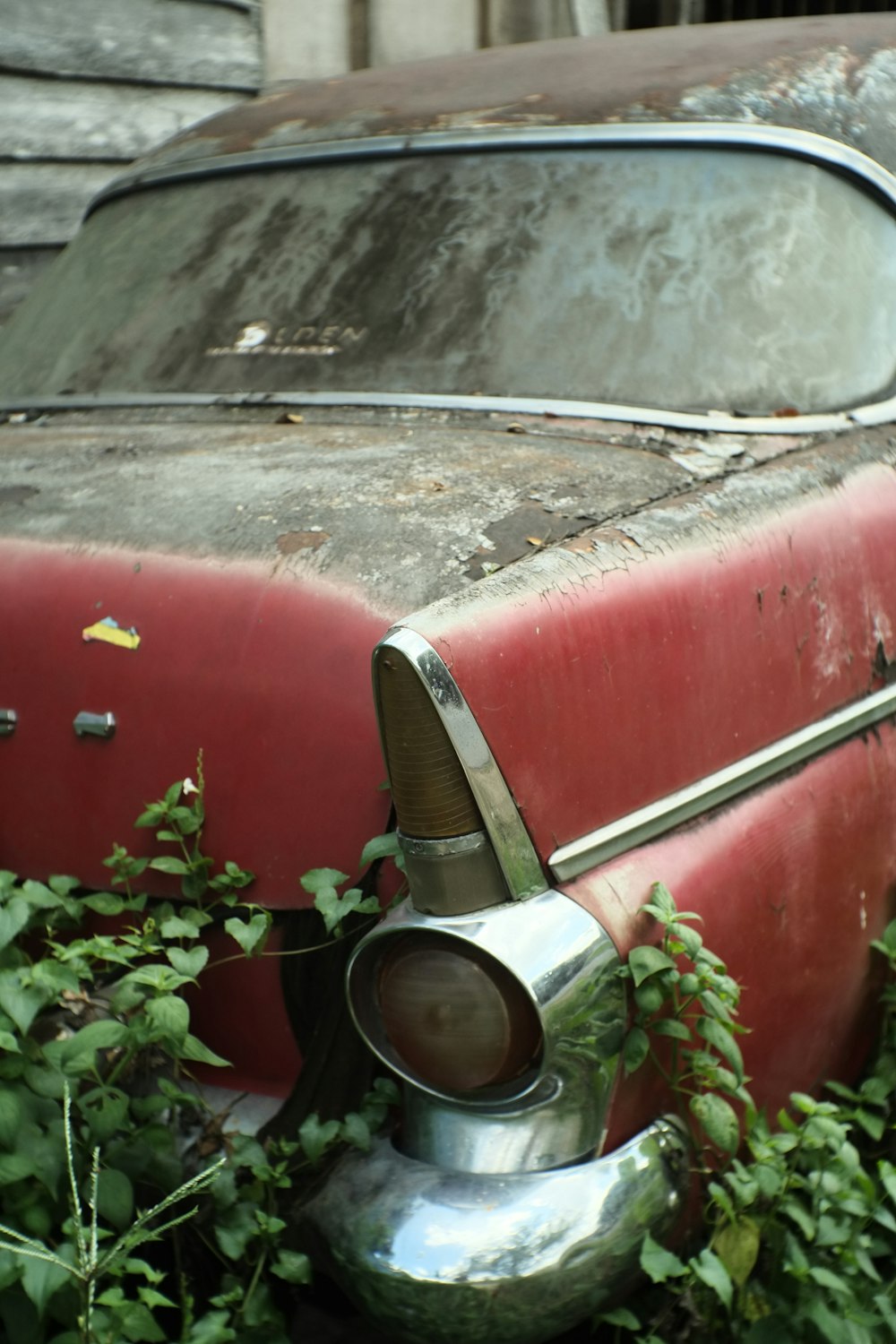 a rusted out car sitting in the grass