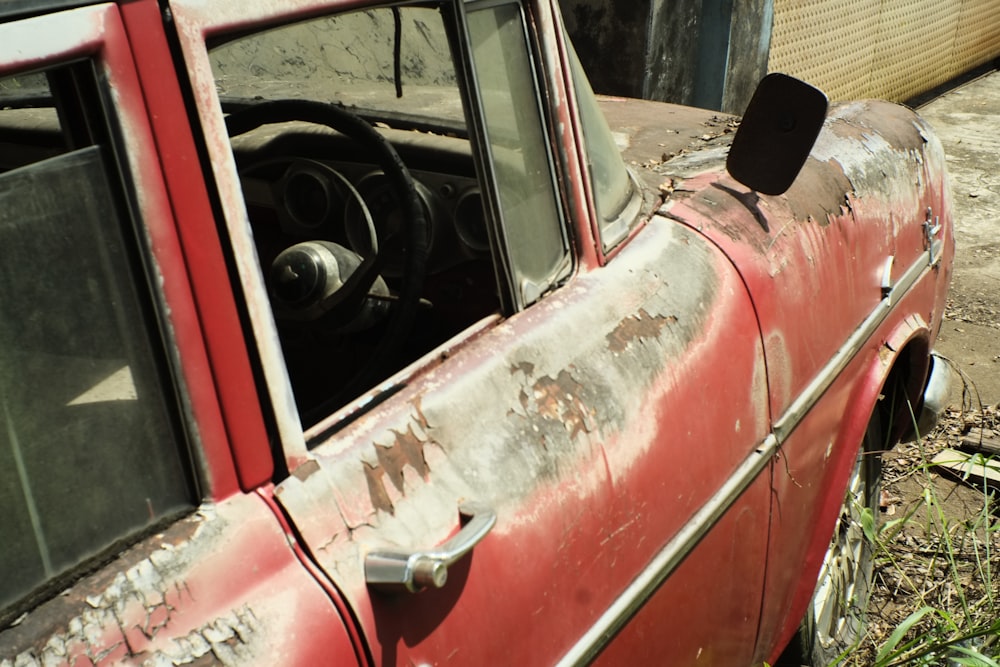 a rusted out red truck parked next to a building