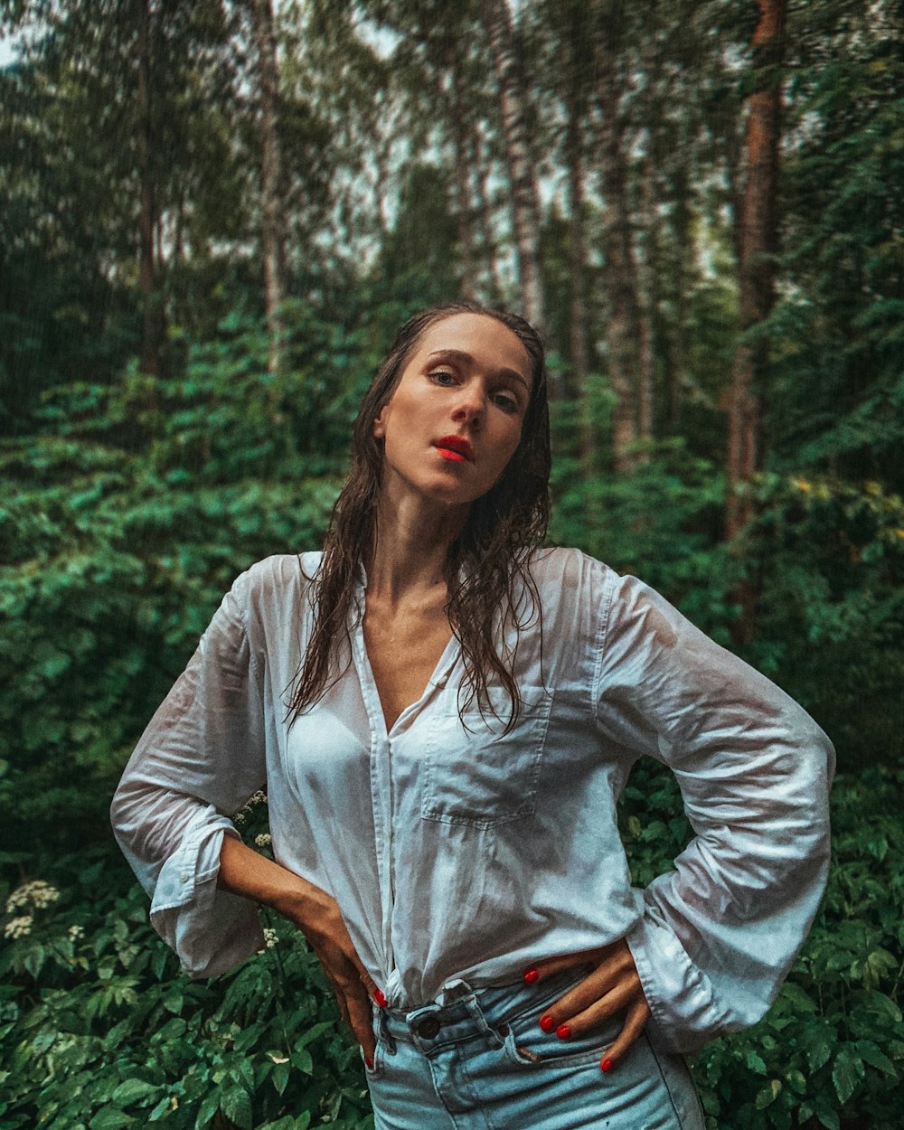 una donna in piedi in una foresta con le mani sui fianchi