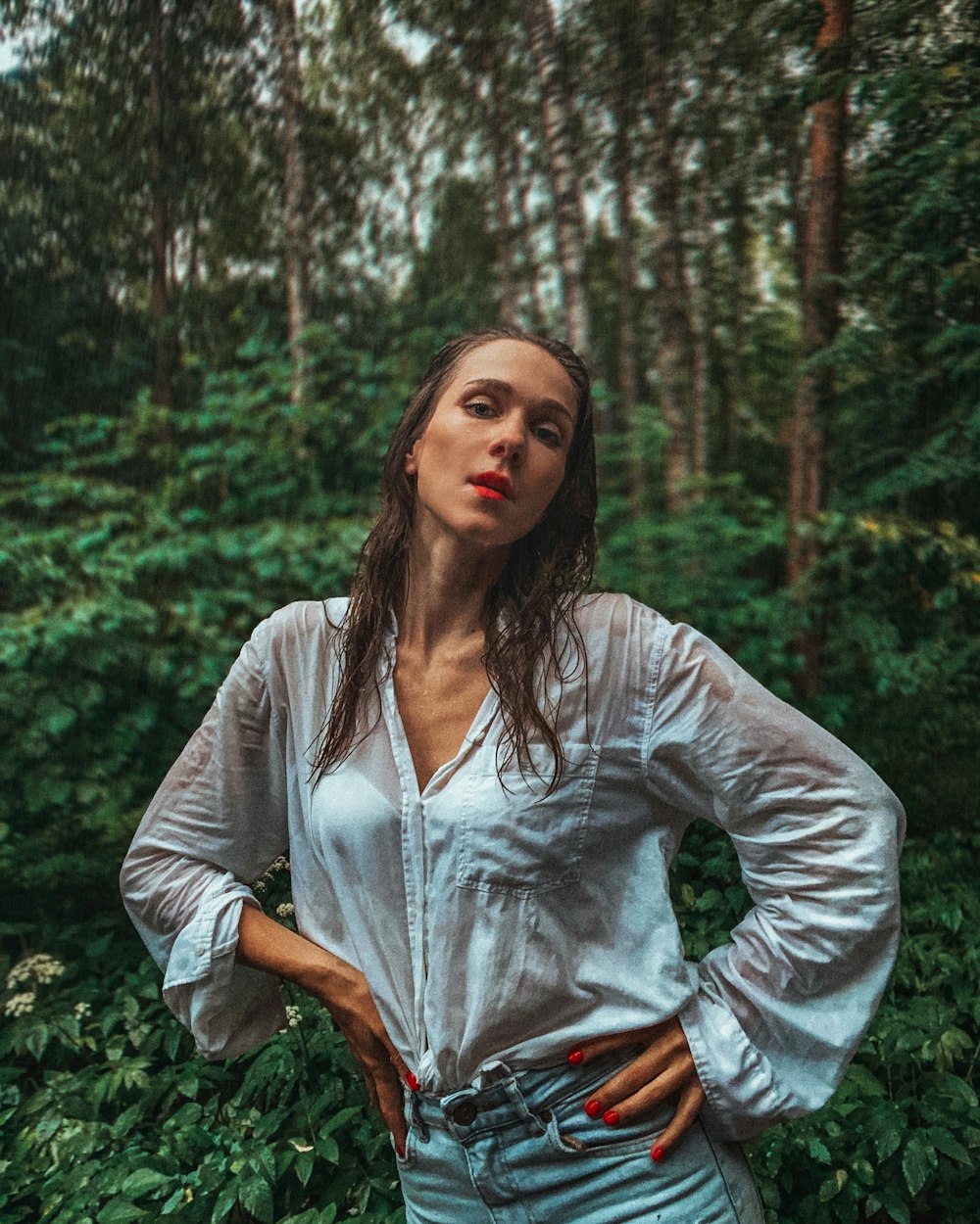 a woman standing in a forest with her hands on her hips