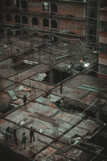 A group of structural engineers reviewing blueprints on a construction site with steel frameworks in the background.