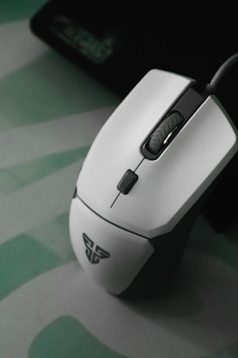 A modern computer mouse resting on a textured gaming mousepad.