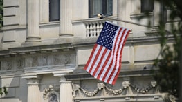 Maryland state flag waving outside a historic courthouse.
