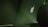 An image featuring the back of an open laptop displaying the illuminated logo. The laptop sits on a table in a dimly lit environment, with the scene predominantly bathed in shades of green.