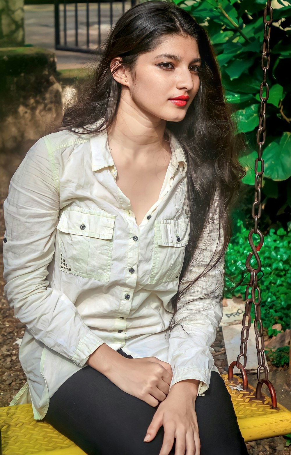 a woman sitting on a swing in a park