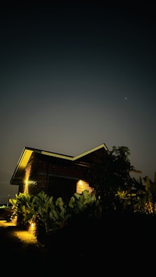 Evening shot of a brick house illuminated by warm outdoor lighting.