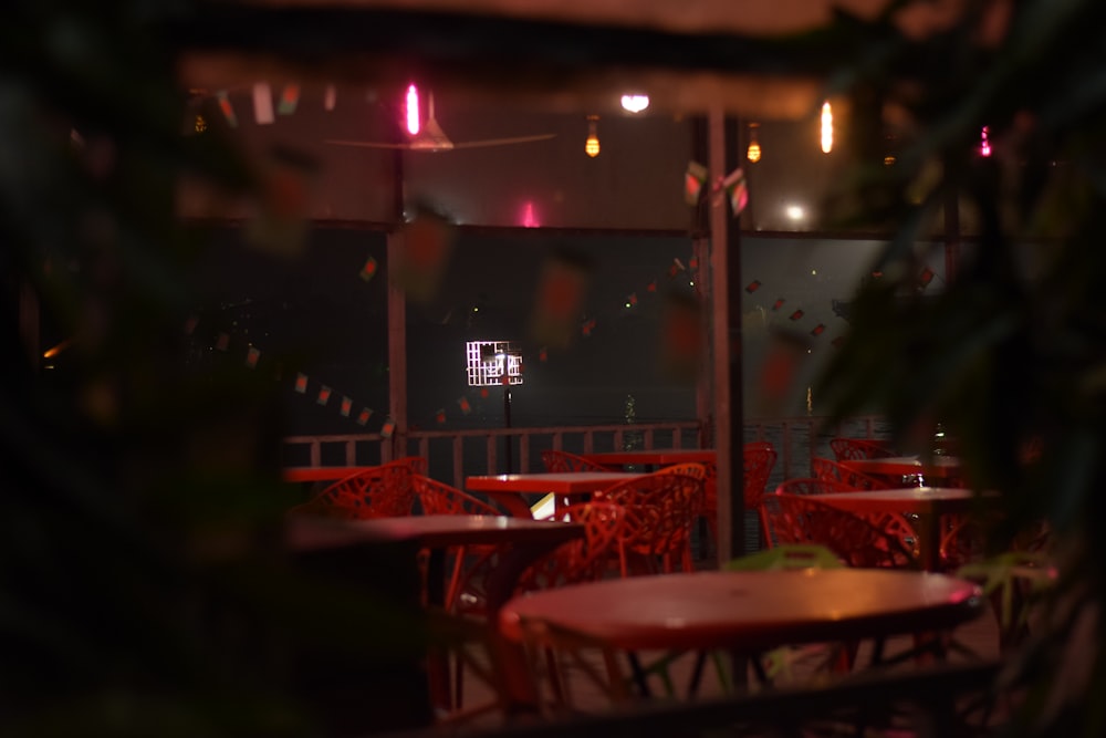 a restaurant with red chairs and tables at night