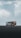 A tour bus with the text 'The Plane Wreck Shuttle' is parked on a desolate and rocky landscape. The sky is overcast with thick clouds, giving the scene a moody atmosphere.