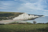 a large body of water sitting next to a lush green field