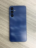 a blue samsung phone sitting on top of a wooden table