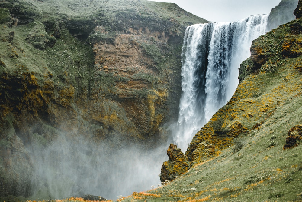 a large waterfall with a lush green hillside