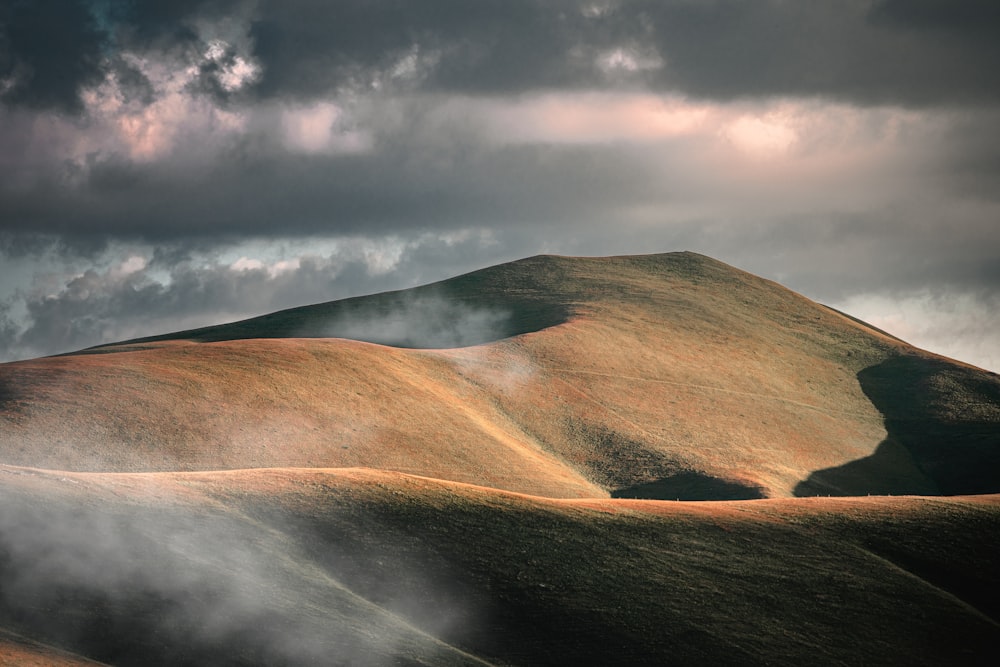 a hill covered in clouds under a cloudy sky