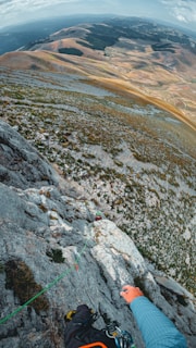 A brave climber scaling a rocky face with a breathtaking fjord view stretching into the distance.