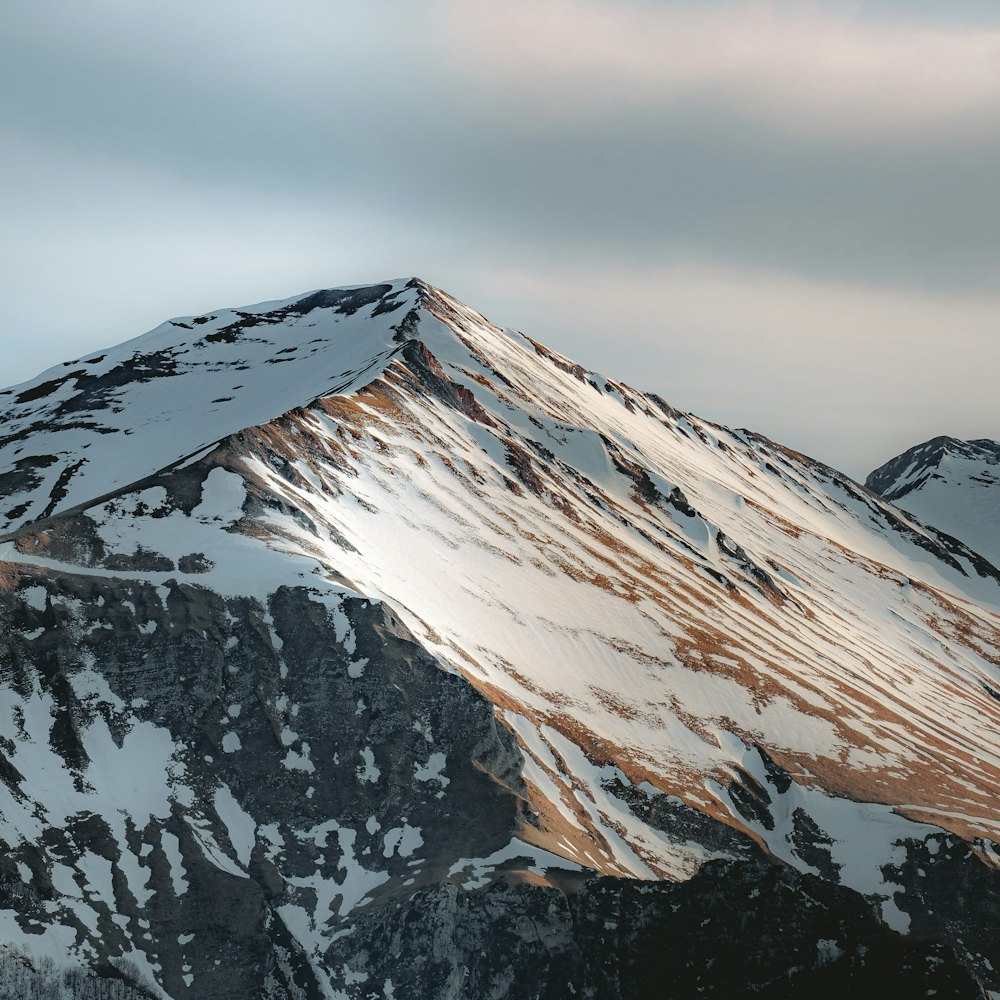 a mountain covered in snow with a sky background