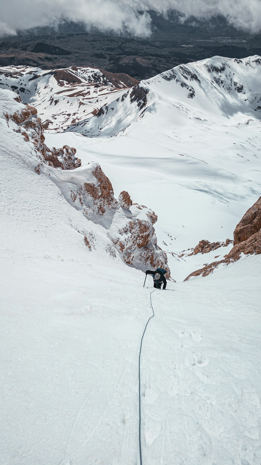 a man walking up the side of a snow covered mountain
