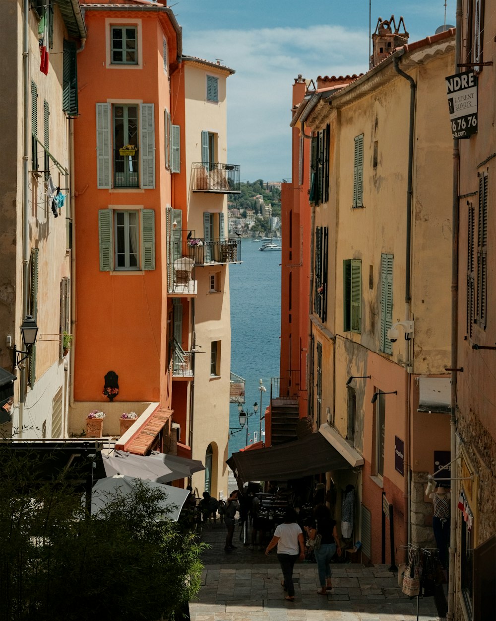 a group of people walking down a street next to a body of water