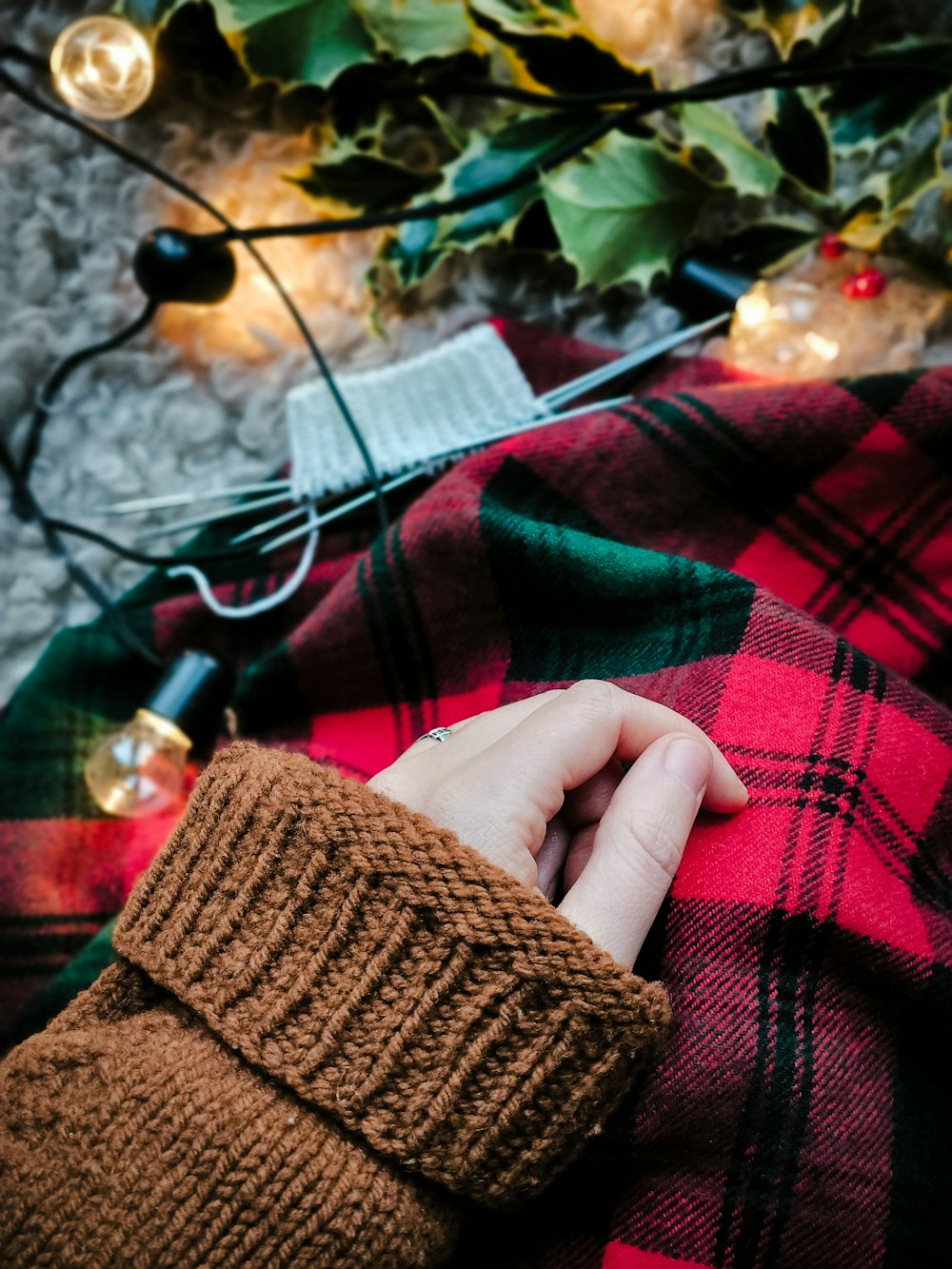 a person's hand resting on a plaid blanket