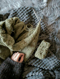 a knitted sweater and a pair of knitting needles