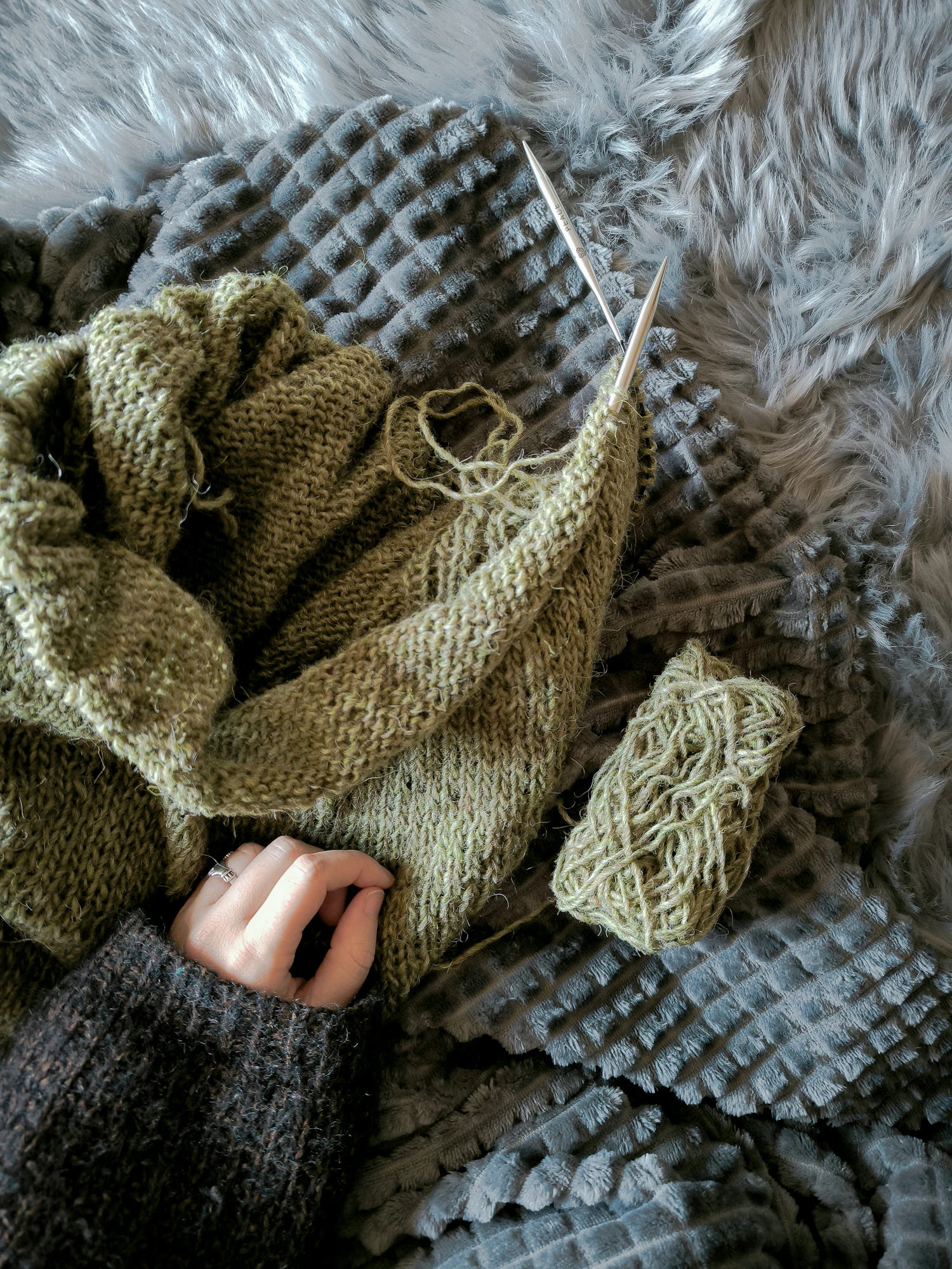 A half-finished knitted jumper with the needles still in it