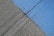 A concrete surface is painted with diagonal lines, featuring a section in blue and another in gray. The texture is rough, with visible grooves and small debris scattered on the surface.