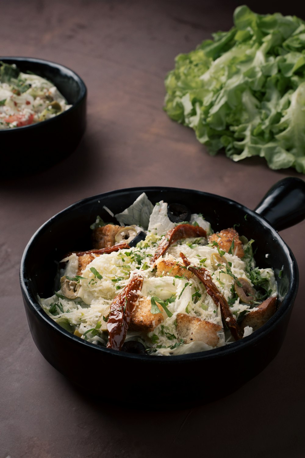 a bowl of food sitting on a table next to some lettuce