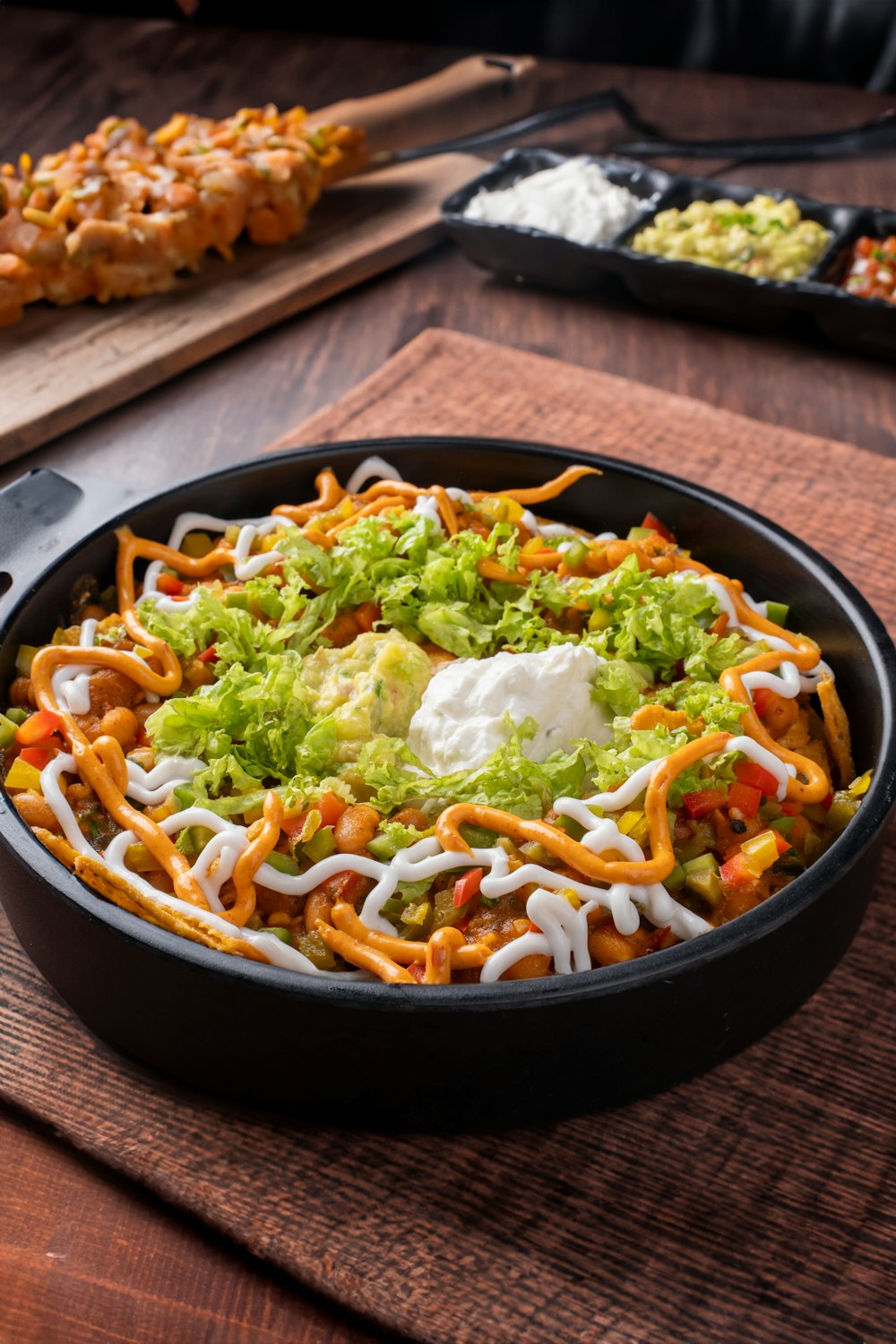 a skillet filled with taco salad on top of a wooden table