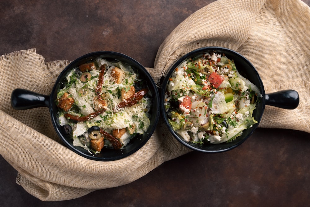 a couple of black bowls filled with food on top of a table