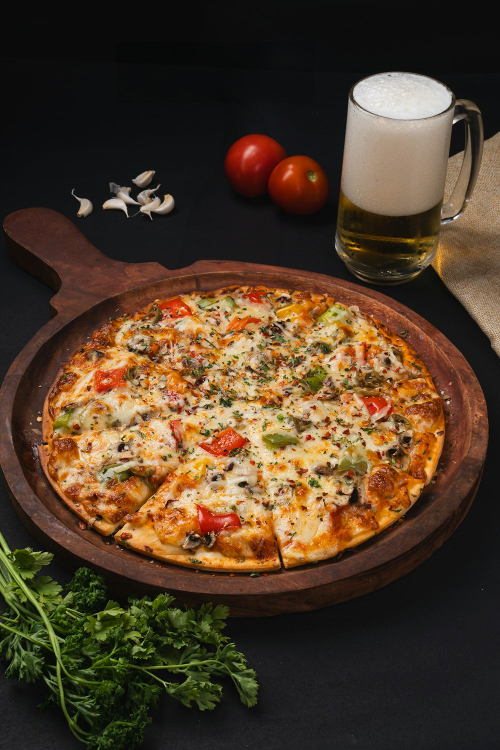 a pizza sitting on top of a wooden pan next to a glass of beer