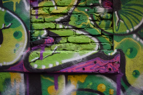 A colorful mural painting in progress, showing brushstrokes and lively textures on a large wall.