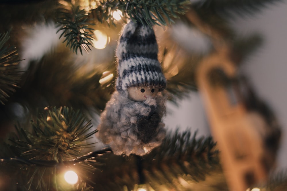 a knitted gnome ornament hanging from a christmas tree