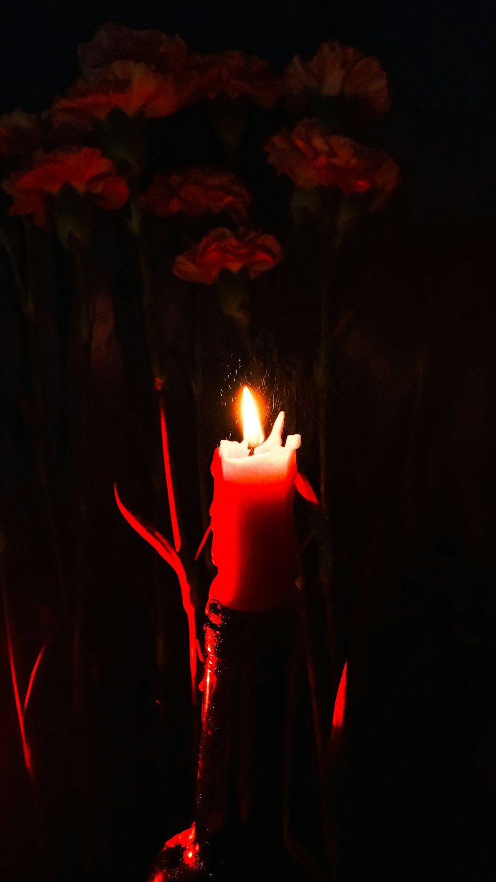 a lit candle sitting in the middle of a field of flowers