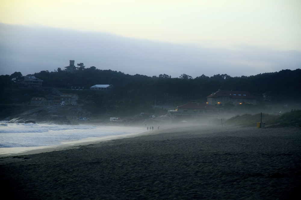 a foggy beach with houses in the distance