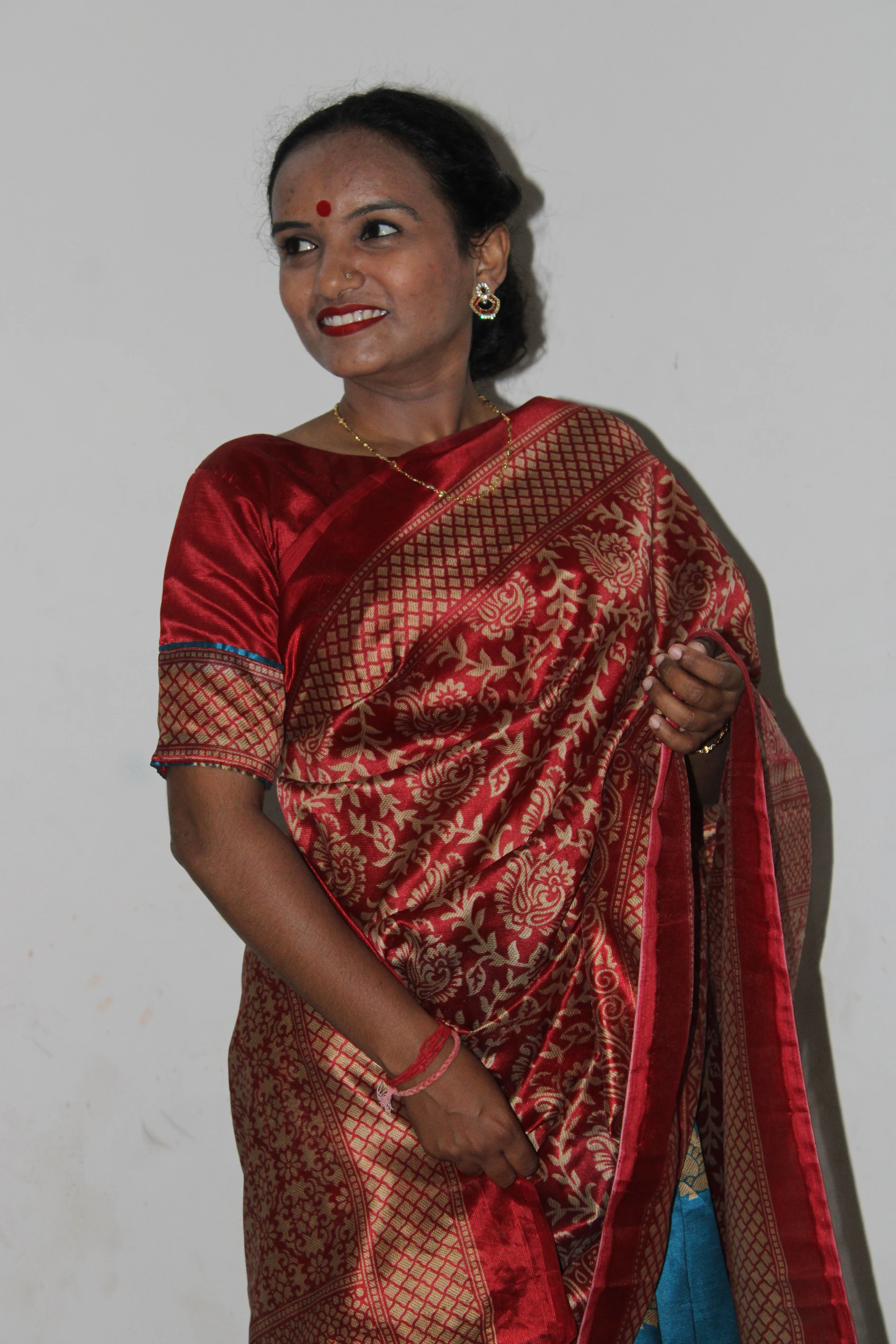A close-up of a vibrant silk saree with intricate gold embroidery, gracefully draped on a smiling client.