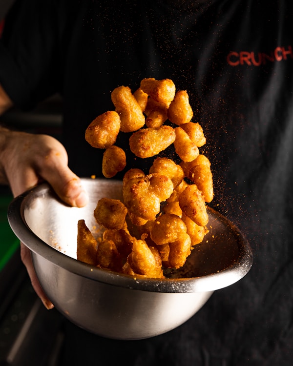 A person holding a bowl of fried food