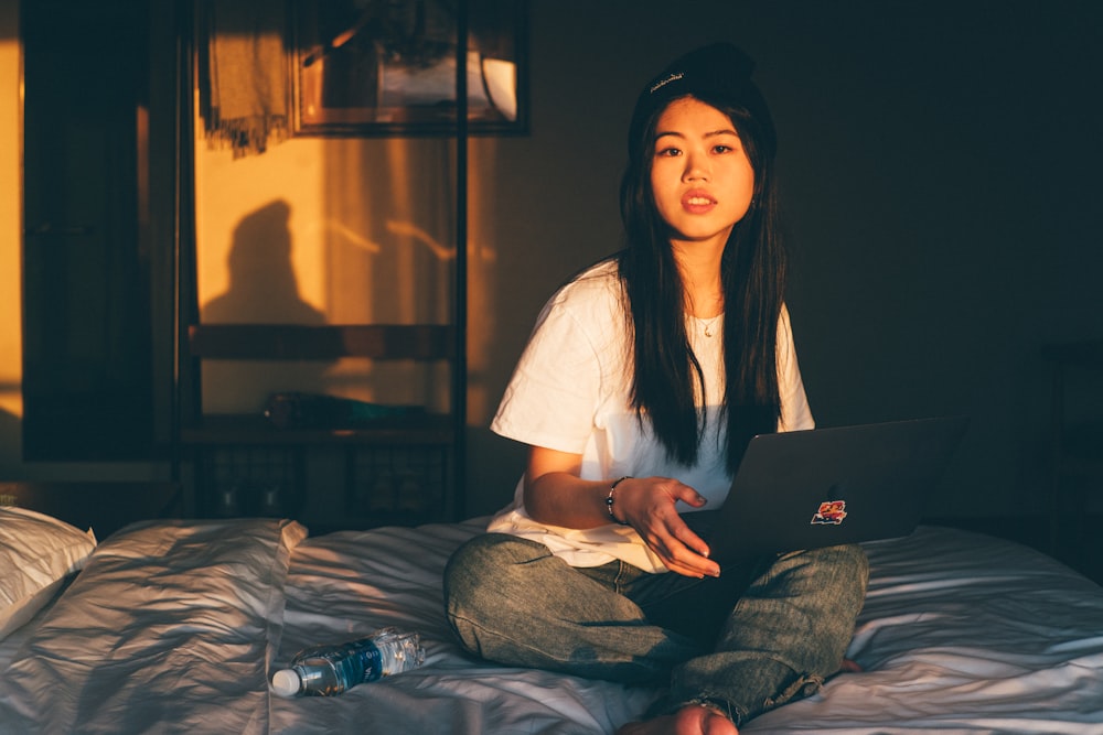 a woman sitting on a bed using a laptop computer