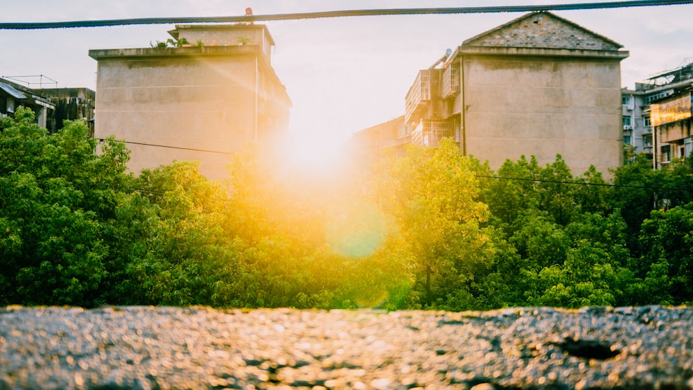 the sun shines through the trees in front of some buildings