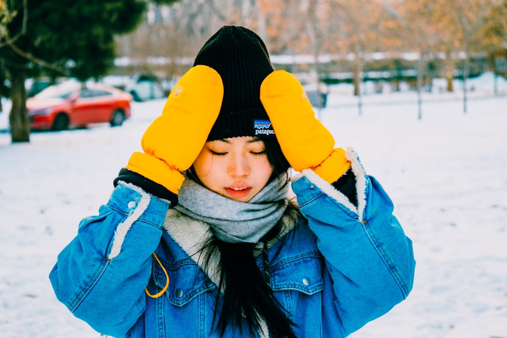 a woman wearing a blue jean jacket and a black and yellow beanie