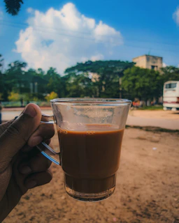 A happy customer holding a melotea cup with a city park in the background on a sunny day.