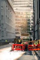 Workers managing waste removal with bins and trucks on a construction site.