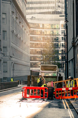 A professional team carefully handling waste disposal containers at a busy urban site.