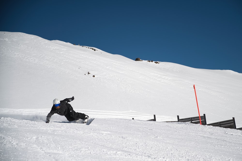 a man riding a snowboard down a snow covered slope