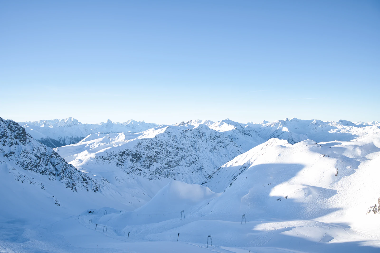 A skier carving on a wide groomed snow slope