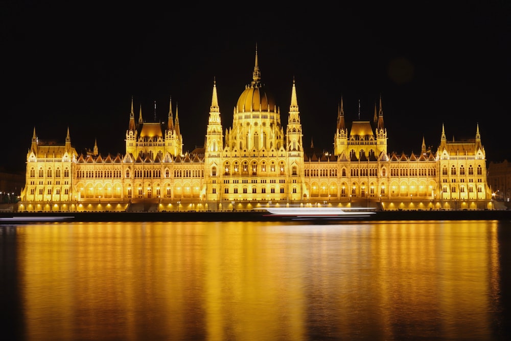 a large building lit up at night with water in front of it