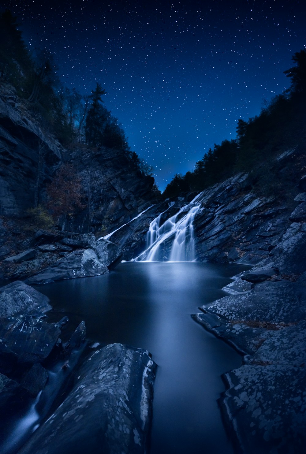 une photo à longue exposition d’une chute d’eau la nuit