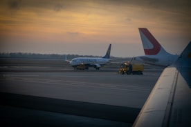 An airport runway with airplanes preparing for takeoff at sunset