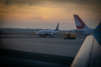 An airport runway with airplanes preparing for takeoff at sunset