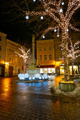 Night scene of the plaza with lively shops and warm glowing lights.